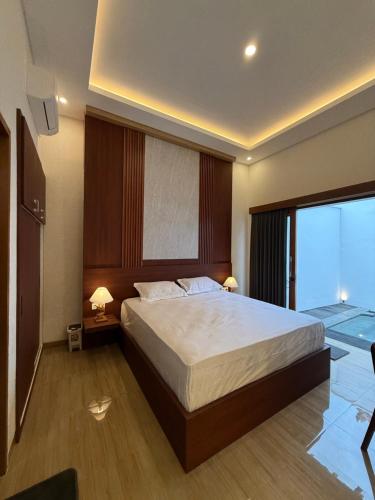 a bedroom with a large bed and a large window at Adi Villa in Darmasaba