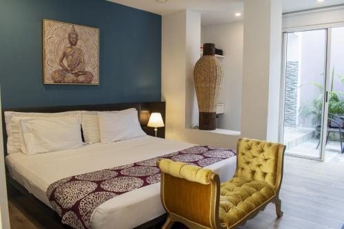 a bedroom with a large bed and a chair at Malik Hotel Boutique in Cali