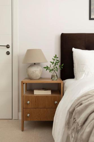 a bed with a night stand with a lamp on it at The J Luxury Apartments Near Mahane Yehuda - Perfect for Shabbat Stays in Jerusalem