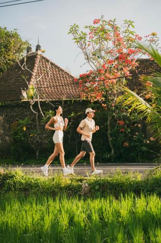a man and a woman running down a street at Magical Jungle Resort in Ubud