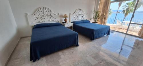 two beds in a bedroom with a view of the ocean at PlayaSol las Hadas in Manzanillo