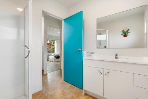 a bathroom with a blue door and a sink at Ocean Road Beach House in Whangamata