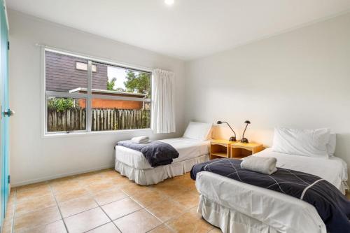 two beds in a room with a window at Ocean Road Beach House in Whangamata