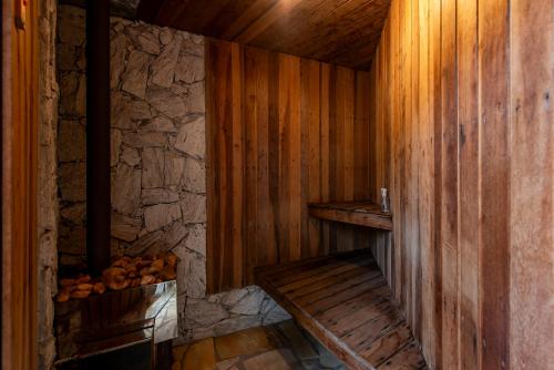 a wooden sauna with a bench and a stone wall at Casa dos Pinheiros in Resende