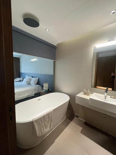 a bathroom with a tub and a sink and a bed at Flamingo Cat Ba Beach Resort in Cat Ba