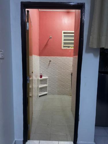 a door leading into a bathroom with a red wall at LOT 1423 Homestay Lonek-Batu Kikir in Bahau