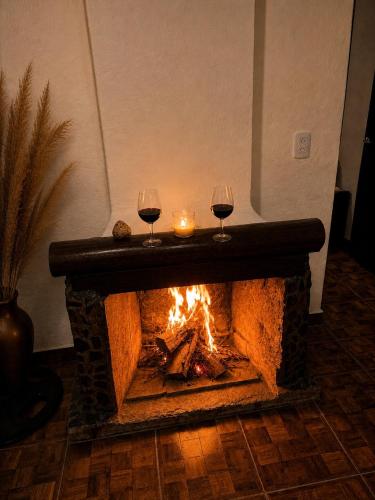 two glasses of wine sitting next to a fireplace at Cabañas El Cardón in Maimará