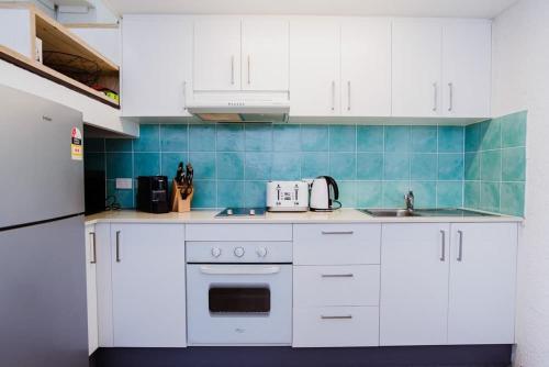 a kitchen with white cabinets and a sink and a refrigerator at Binishell Igloo 6 - Famous Beachfront Dome with Pool in Trinity Beach