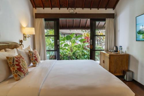 a bedroom with a large bed with a large window at Goya Courtyard Ubud in Ubud