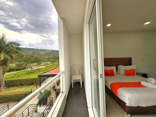 a bedroom with a bed and a balcony with a view at Hotel Palmeras De Luz in Moniquirá