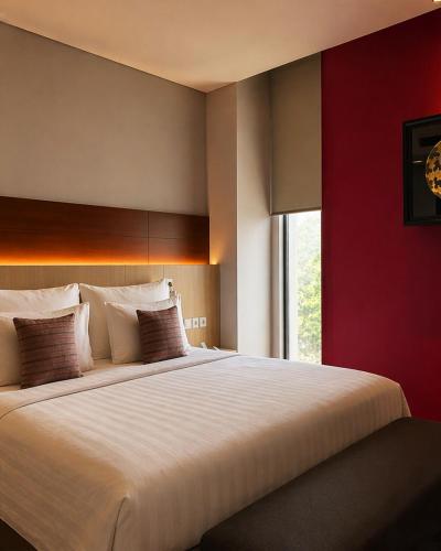 a bedroom with a large bed with a red wall at Ra Premiere Simatupang in Jakarta