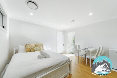 a white bedroom with a bed and a dining room at 1B house beachside comfy stay in Collaroy