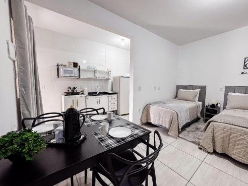 a living room with a table and a bedroom at Apê completo p/ 3 • vaga + Wi-Fi in Brusque