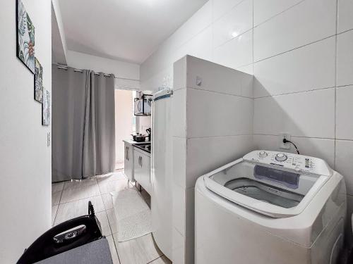 a small white bathroom with a washing machine in it at Apê completo p/ 3 • vaga + Wi-Fi in Brusque