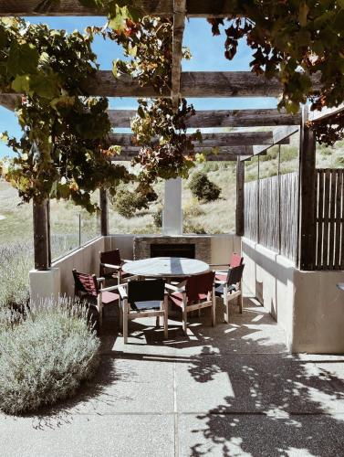 a table and chairs sitting under a wooden pergola at The Retreat at Carrick Vineyard in Cromwell