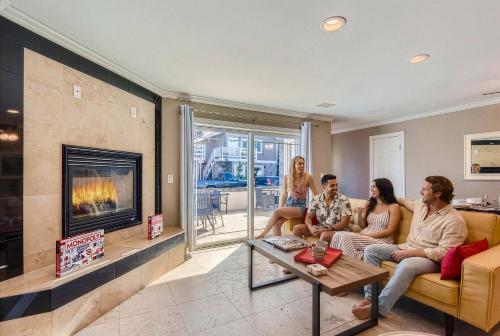 a group of people sitting on a couch in a living room with a fireplace at Awesome 3BR 2BTH 1 Block To Beach C2 in Newport Beach