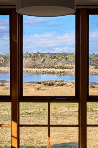 a window with a view of a river seen through it at Shepherd's Cottage at Lisdillon Estate in Little Swanport
