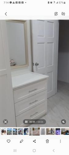a bathroom with a white dresser and a mirror at Sunset Apartment in Grand Anse
