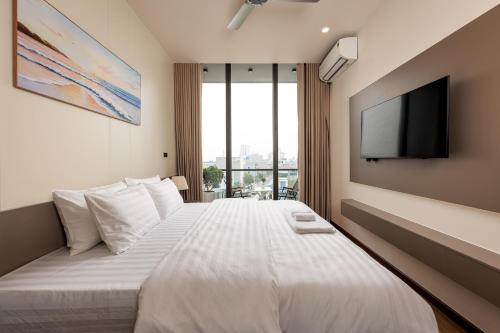 a bedroom with a large white bed with a flat screen tv at Cyan Sầm Sơn Hotel in Sầm Sơn