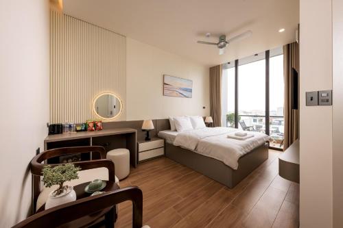 a bedroom with a bed and a table with a desk at Cyan Sầm Sơn Hotel in Sầm Sơn