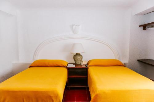 two yellow beds in a room with a table with a lamp at Hotel Antillano Cancun in Cancún