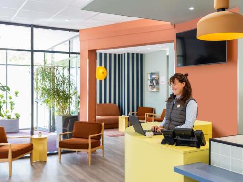 a woman sitting at a desk in an office at Aparthotel Adagio Access Toulouse Jolimont in Toulouse