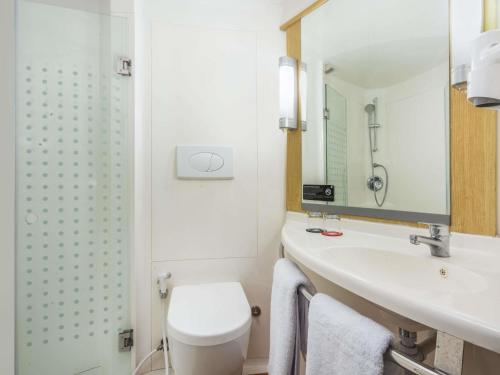 a bathroom with a toilet and a sink at Ibis Jakarta Senen in Jakarta