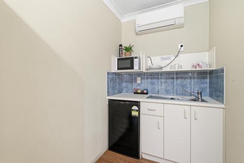 a kitchen with white cabinets and a black dishwasher at Ocean Parade Motel in Coffs Harbour