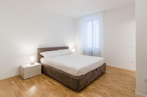 a white bedroom with a large bed and a window at Alla Loggia in Udine