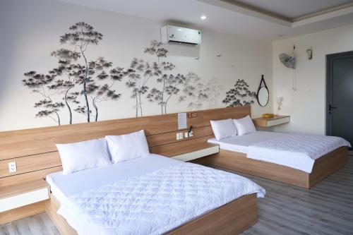 a bedroom with two beds and a wall with a mural at Hotel Tâm Đan in Ðông Tác (1)