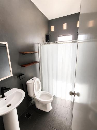 a bathroom with a toilet and a shower and a sink at Villas Flora Bella Sunflower in Dauis