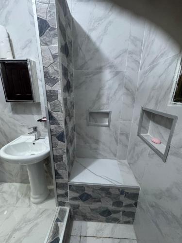 a white bathroom with a sink and a shower at Raqsea House in Monrovia