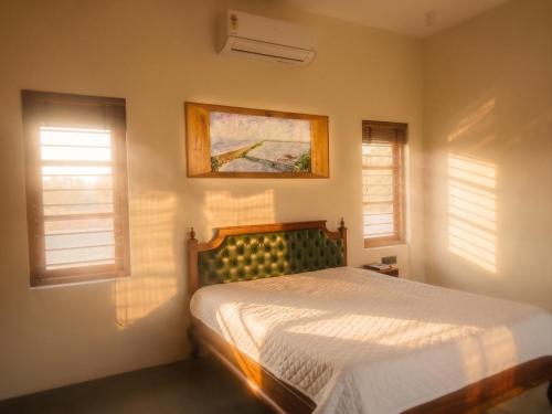 a bedroom with a bed and two windows at Nilah Private Pool Villa in Kappil