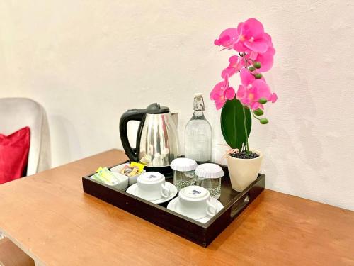 a tray with a tea set and a flower on a table at Suite Room The Megatruh in Kejayan