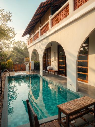 a swimming pool in front of a house at Nilah Private Pool Villa in Kappil