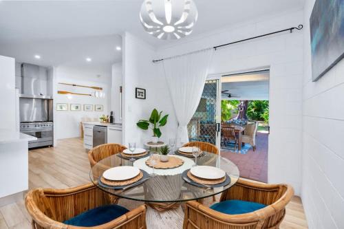 a dining room with a glass table and chairs at Trinity Charm - Beachside Family Getaway with Pool in Trinity Beach
