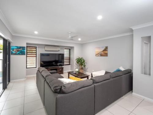 a living room with a couch and a flat screen tv at Tropical Pool Sanctuary in Kewarra Beach, Family and Dog Friendly in Kewarra Beach