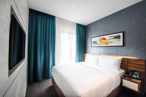 a bedroom with a large white bed and blue curtains at The Smith House in Pantai Cenang