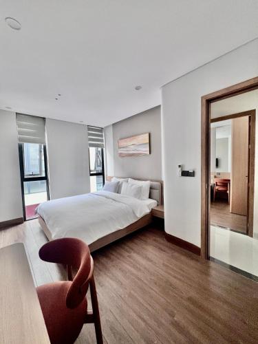 a bedroom with a bed and a chair and a window at SunQ Haven in Meyhomes in Phú Quốc