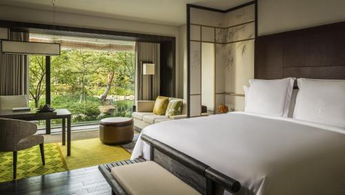 Four Seasons Hotel Kyoto في كيوتو: غرفة نوم مع سرير أبيض كبير ومكتب