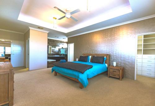 a bedroom with a blue bed and a ceiling fan at Marina Views Mindarie in Mindarie