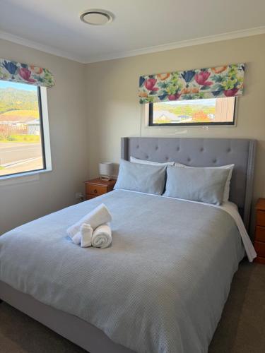 a bedroom with a large bed with two windows at The Bach in Coromandel Town
