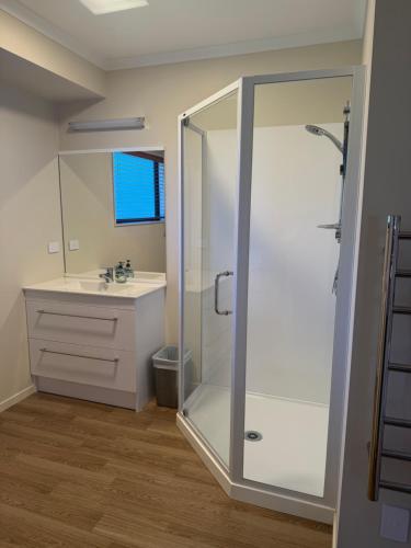 a bathroom with a shower and a sink at The Bach in Coromandel Town