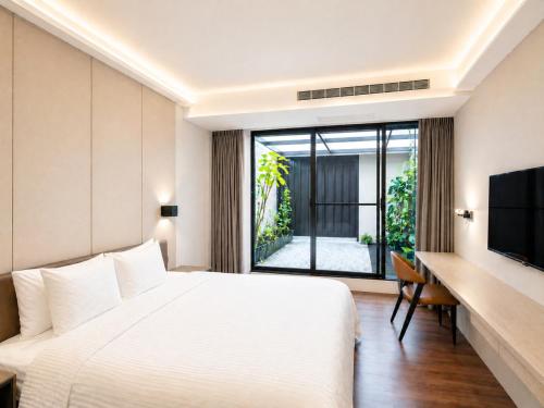 a bedroom with a bed and a desk and a television at Innk in Taichung