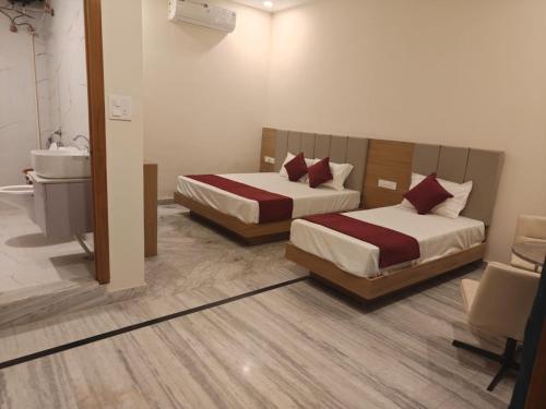 two beds in a hotel room with a bathroom at Blue Breeze in Haridwār
