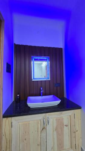 a bathroom with a sink and a blue light at Sunrise Inn in Yelagiri