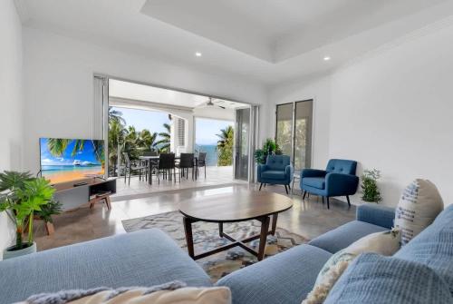 a living room with a blue couch and a table at The Marron Bloom - Beachfront Boutique Bliss in Palm Cove
