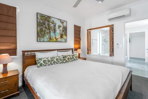 a bedroom with a large bed and a mirror at The Marron Bloom - Beachfront Boutique Bliss in Palm Cove