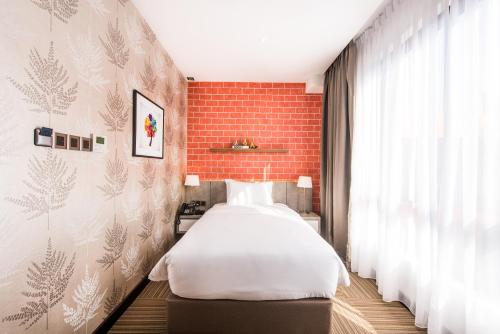 a bedroom with a bed and a brick wall at The Smith House in Pantai Cenang