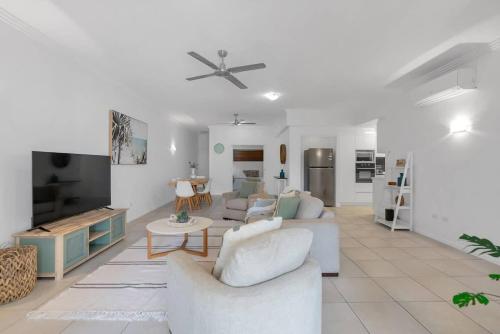 a living room with white furniture and a flat screen tv at 'Eclipse' A Poolside Family Escape in the CBD in Cairns